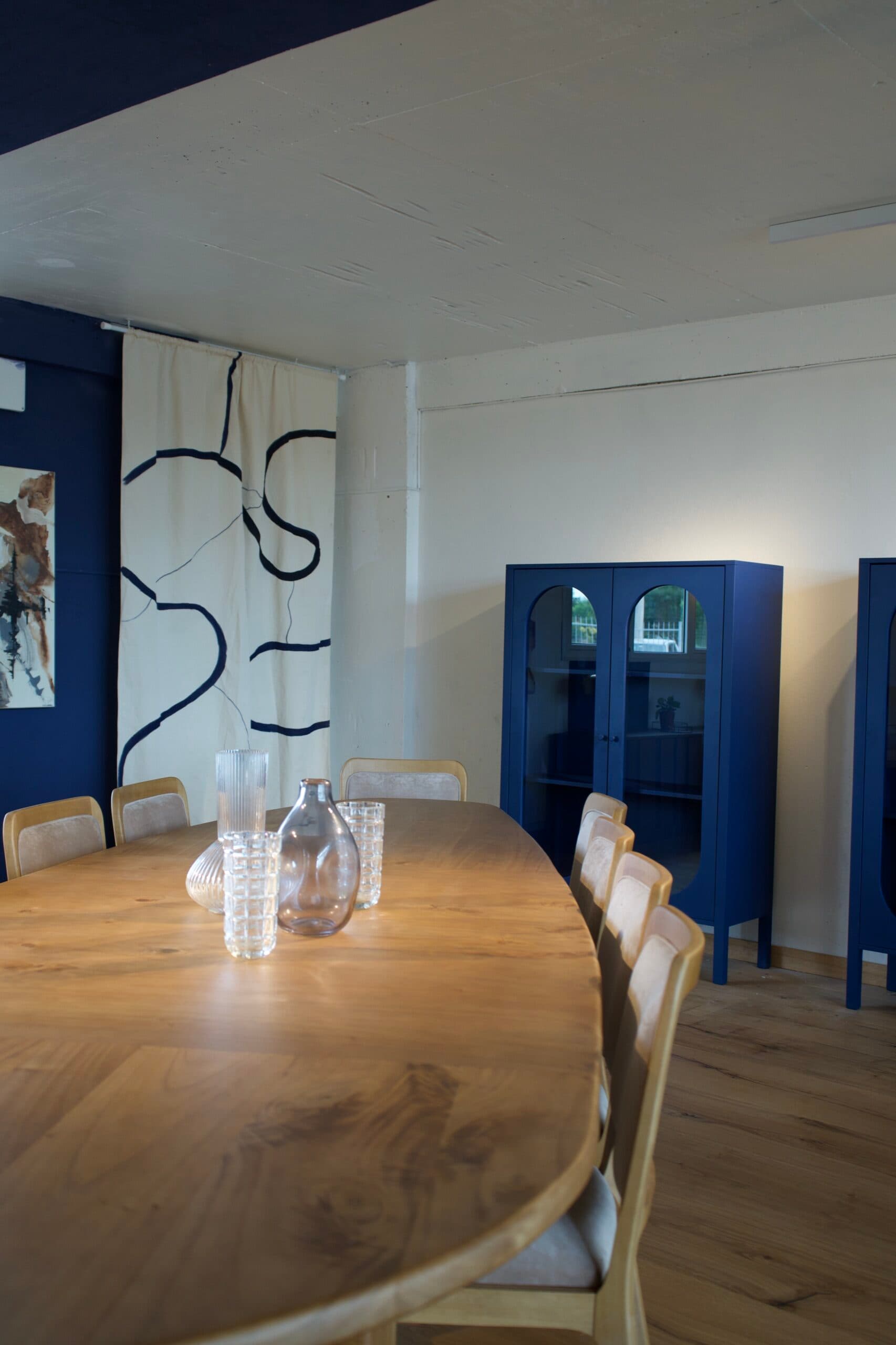 Comedor con pared azul, obra de arte y vitrinas